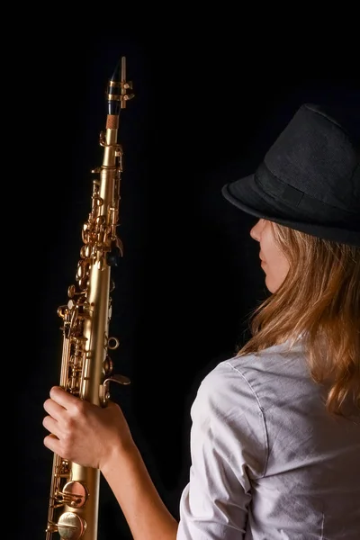 Soprano saxofone nas mãos de uma menina em um fundo preto — Fotografia de Stock