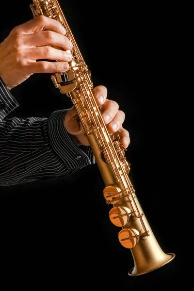 Saxofón soprano en manos sobre fondo negro — Foto de Stock