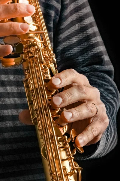 Saxofón soprano en las manos de un chico sobre un fondo negro — Foto de Stock