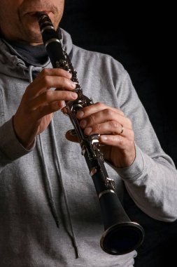 Klarnet, siyah arka plandaki bir adamın ellerinde.