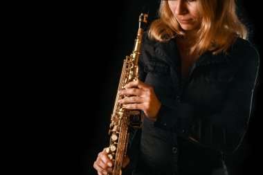 Siyah arka plandaki bir kızın elinde soprano saksafon.