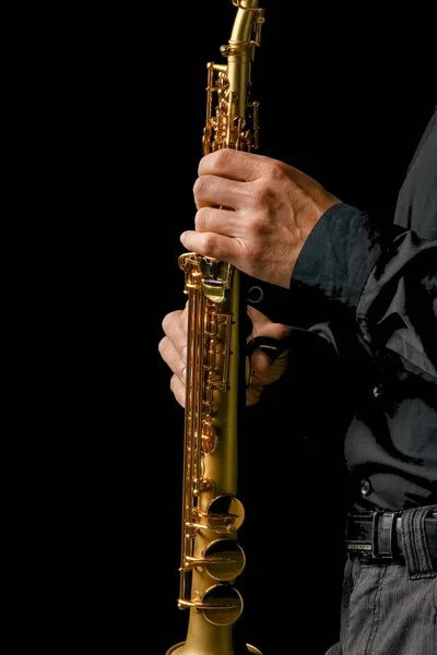Саксофон сопрано в руках на черном фоне — стоковое фото