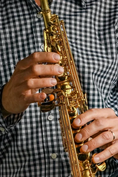 Saxofón soprano en manos sobre fondo negro — Foto de Stock