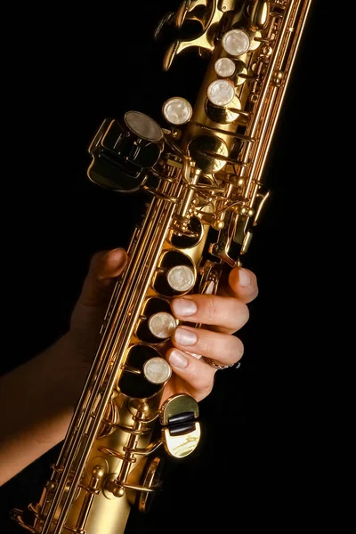 Sopraan saxofoon in handen op een zwarte achtergrond — Stockfoto