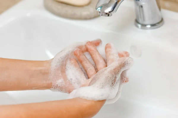 Hygiene concept. Washing hands with soap under the faucet with w