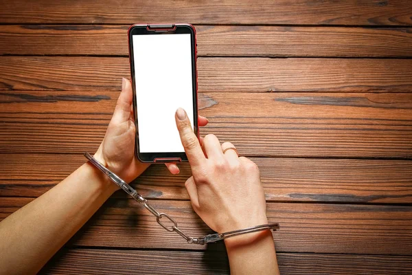 Teléfono con manos adicción sobre un fondo de madera — Foto de Stock