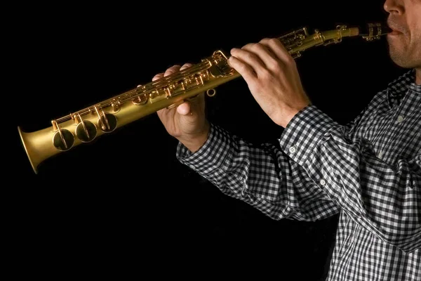 Soprano saxofone em mãos sobre um fundo preto — Fotografia de Stock