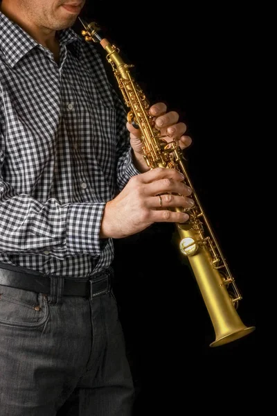 Soprano saxophone in hands on a black background Royalty Free Stock Images