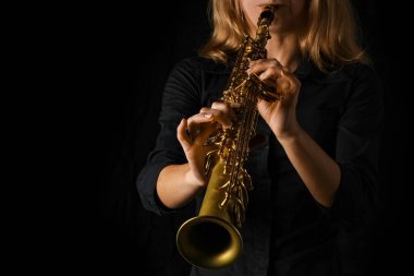 soprano saxophone in hands on a black background clipart