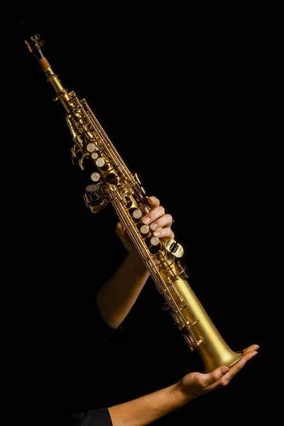 Sopransaxophon in den Händen auf schwarzem Hintergrund — Stockfoto