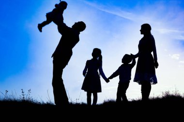 Deniz kenarında mutlu bir aile, doğanın siluetinde.
