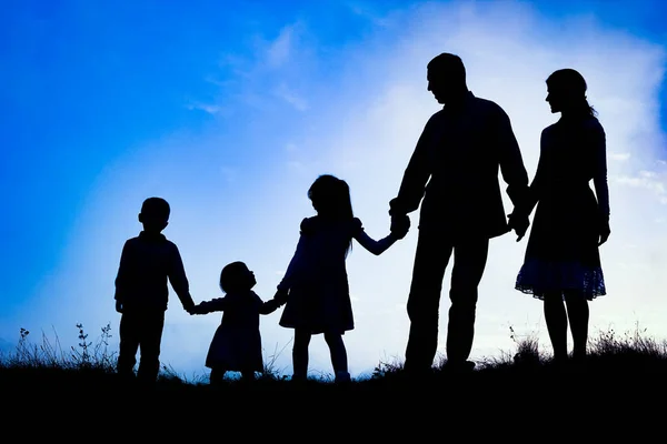 Familia feliz junto al mar en la silueta de la naturaleza de fondo — Foto de Stock