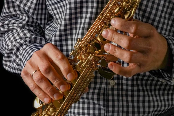 Saxofón soprano en manos sobre fondo negro — Foto de Stock