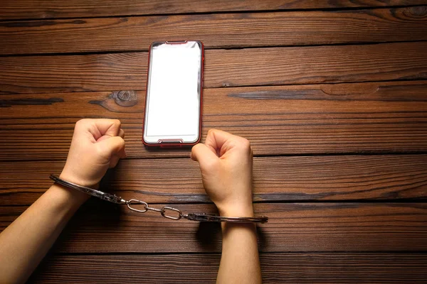 Teléfono con manos adicción sobre un fondo de madera — Foto de Stock