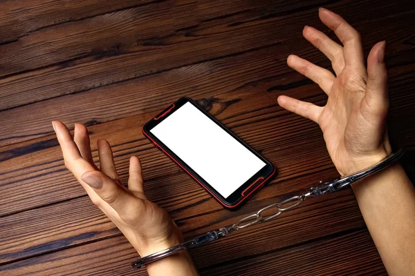 Teléfono con manos adicción sobre un fondo de madera — Foto de Stock