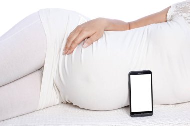 Mutlu hamile kız beyaz arka planda yatıyor.