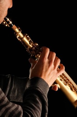 Siyah arka plandaki bir adamın elinde soprano saksafon.