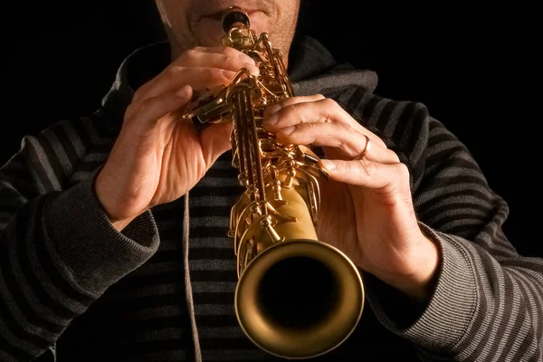 Saksofon sopranowy w rękach faceta na czarnym tle — Zdjęcie stockowe