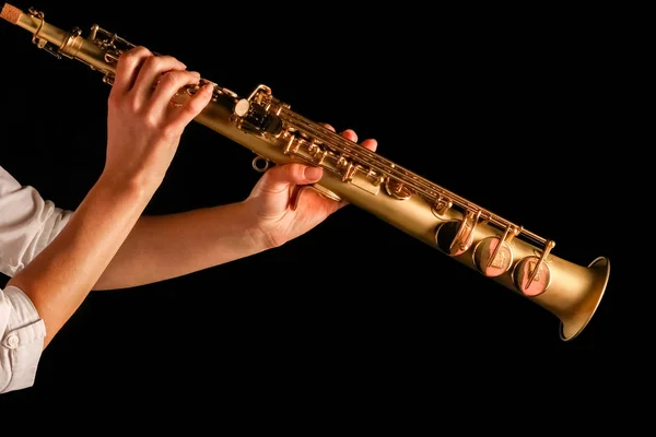Saxofón soprano en manos de una chica sobre un fondo negro — Foto de Stock