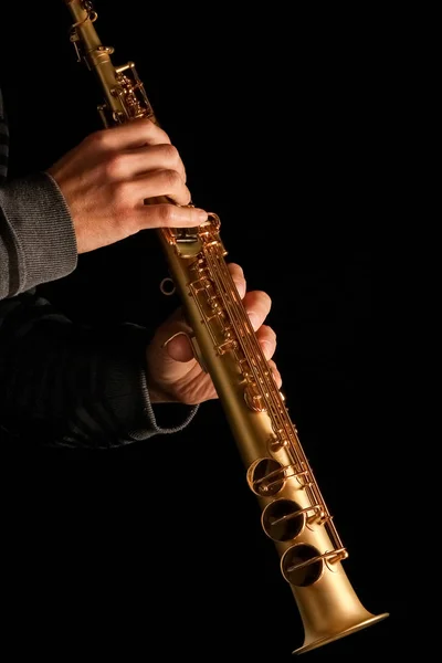 Сопрано-саксофон в руках парня на черном фоне — стоковое фото