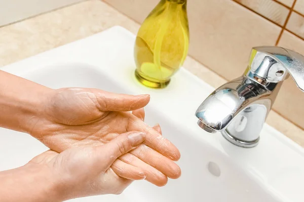 Washing hands with soap under the faucet with water