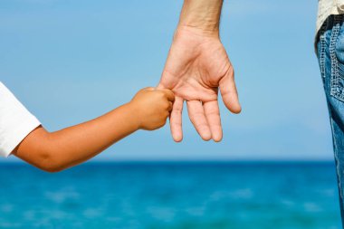 Mutlu baba, Yunan Denizi kıyısında bir çocuğun elini tutuyor.