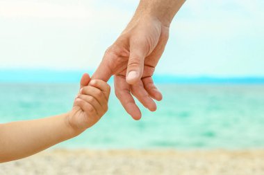doğada deniz tarafından mutlu bir ebeveyn ve çocuğun güzel elleri