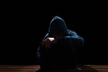 Siyah arkaplanda dizüstü bilgisayarı olan bir bilgisayar korsanı