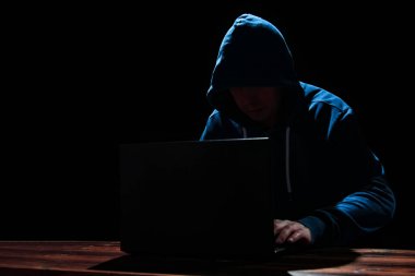 Siyah arkaplanda dizüstü bilgisayarı olan bir bilgisayar korsanı