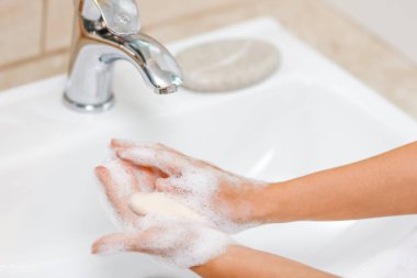  Musluğun altında sabunla ellerini yıkamak, suyla.