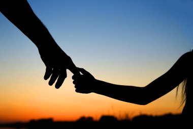 Siluet ebeveyn küçük bir çocuğun elini tutar.