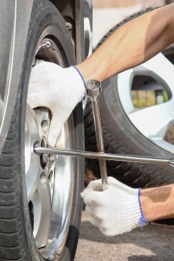 Bir arızadan sonra, bir kişi bir arabanın tekerleğini İngiliz anahtarıyla başka bir tekere değiştirir.