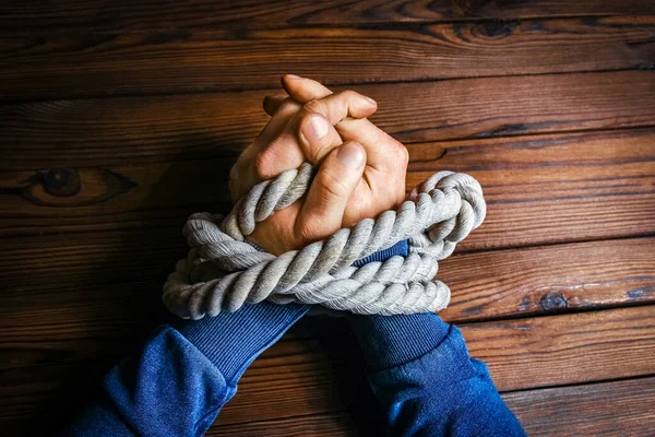 hands with a rope on a wooden background