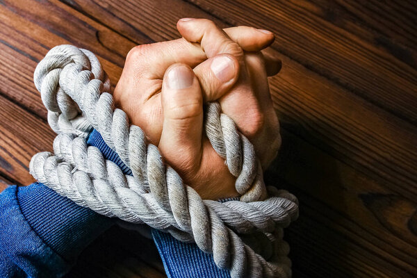 hands with a rope on a wooden background