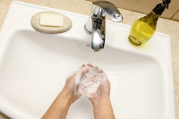 Washing hands with soap under the faucet with water