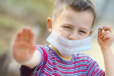 Coronavirus ve hava kirliliği PM2.5 konsepti. PM2.5 'u korumak için maske takan Avrupalı küçük çocuk Corona virüsünün salgınını durdurmak için el hareketi yapıyor. Koronavirüs ve salgın virüsü belirtileri..