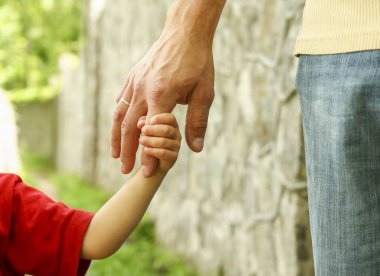 Ebeveyn küçük bir çocuğun elini tutar.
