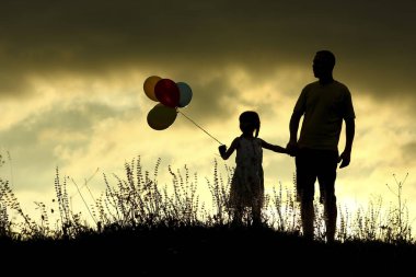 Balonlu çocukları olan mutlu bir aile babasının silueti.
