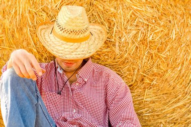 Samanlığın yanındaki samanlıkta bir kovboy. Balyalar sahada mutlu bir adamla. Zor bir günün ardından dinlen..