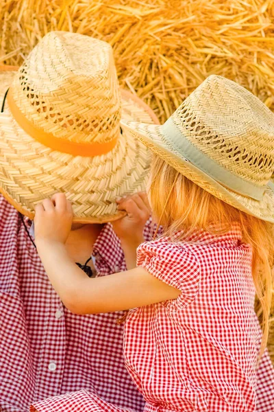 Father with a child playing near a haystack ranch on the field. Happy family have a rest.