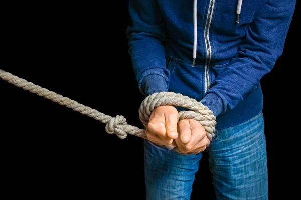 Hands tied with a rope life threatening on a black background. Slavery in business is violence against people.