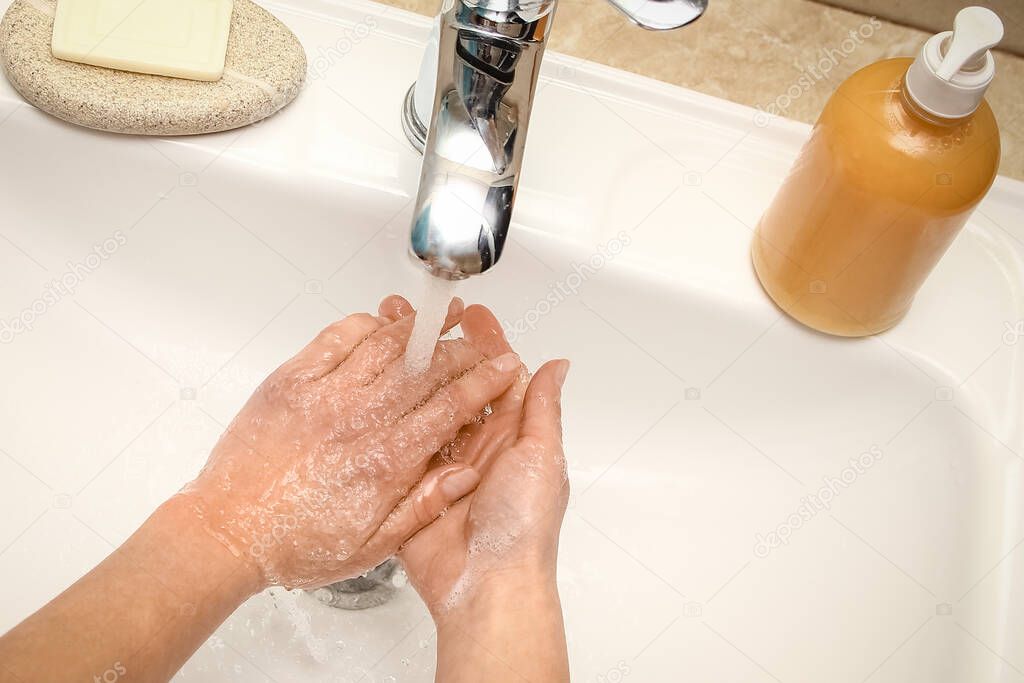 Hands with soap are washed under the tap with water. Clean from infection and dirt and virus.