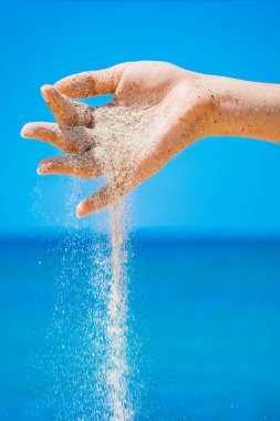 Bir el, doğaya yolculukta denizden kum döker. Tatiller 