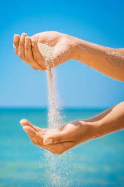 Denizin kenarından kumlar dökülüyor