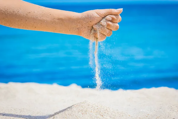 Hands pour sand off the sea on nature on a journey. Vacations at sea sand time passes.