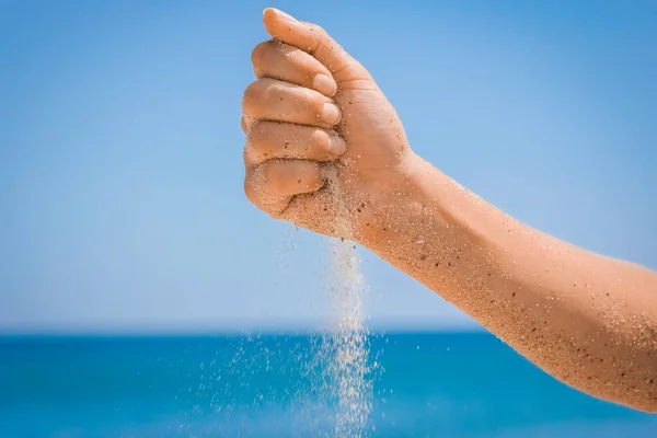 Hands pour sand off the sea on nature on a journey. Vacations at sea sand time passes.