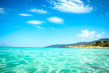 Deniz kıyıdan gelen dalgalarla birlikte doğa arka planında. Kıyının önünde dağlarla.