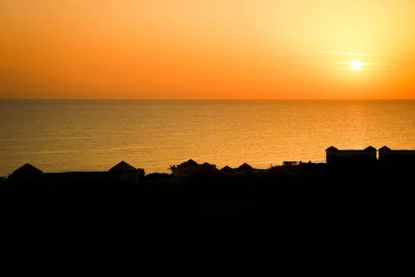 Silhouette of houses on the background of an early sunset of the sea