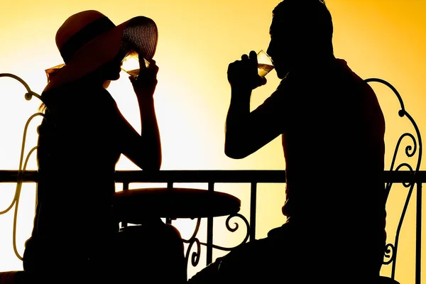 Couple man and woman silhouette drink on a balcony by the sea on the background. Meeting in a double date on the terrace.