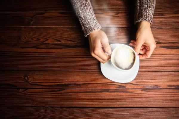 木製の背景に女性の手とコーヒー — ストック写真